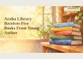 Aruba Library Receives Five Books From Young Author Editorial watercolour illustration of five unlabelled books on a library shelf; not the donated book covers.