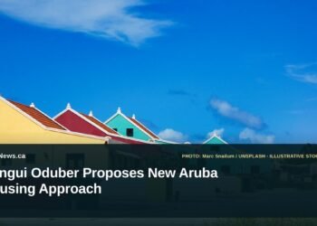 Illustrative stock photo for “Dangui Oduber Proposes New Aruba Housing Approach”: Colorful buildings under a bright blue sky. Photo by Marc Snailum via Unsplash; not a photograph of the specific event. Headline and ArubaNews.ca branding appear in a lower-third news tile.