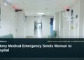 Illustrative stock photo for “Colony Medical Emergency Sends Woman to Hospital”: Empty hospital corridor with benches and doors. Photo by Tasha Kostyuk via Unsplash; not a photograph of the specific event. Headline and ArubaNews.ca branding appear in a lower-third news tile.