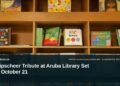 Illustrative stock photo for “Knipscheer Tribute at Aruba Library Set for October 21”: Children’s books arranged on library shelves. Photo by Zoshua Colah via Unsplash; not a photograph of the specific event. Headline and ArubaNews.ca branding appear in a lower-third news tile.