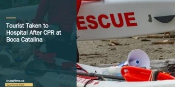 Illustrative stock photograph for “Tourist Taken to Hospital After CPR at Boca Catalina”: 2026-07-10 Vancouver beach lifeguard red jacket carrying surf rescue surfboard. Photograph by Anthony Maw via Unsplash. This is not a photograph of the specific Aruba news event.