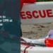 Illustrative stock photograph for “Tourist Taken to Hospital After CPR at Boca Catalina”: 2026-07-10 Vancouver beach lifeguard red jacket carrying surf rescue surfboard. Photograph by Anthony Maw via Unsplash. This is not a photograph of the specific Aruba news event.