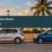 Conceptual editorial illustration; two generic parked compact cars with safe visible separation on a Caribbean urban roadside, distant palm, eye-level wide composition, late-afternoon amber light, neutral gray-blue colors. Not a reconstruction of an accident. Not a documentary image of the reported event.