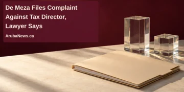 De Meza Files Complaint Against Tax Director, Lawyer Says Conceptual editorial illustration of a blank closed folder and two clear glass blocks against a burgundy background, with the article headline and ArubaNews.ca branding.