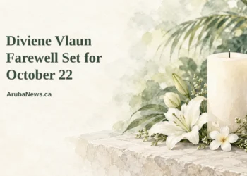 Conceptual editorial illustration of a simple white flower arrangement and a single unlit candle on a pale stone surface with soft out-of-focus caribbean foliage, with the article headline and ArubaNews.ca branding.