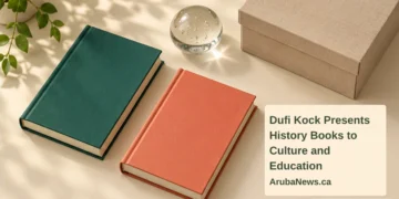 Dufi Kock Presents History Books to Culture and Education Conceptual editorial still life of two blank hardback books, an archival box and glass paperweight, with the article headline and ArubaNews.ca branding; not the actual donated book covers.