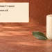 Conceptual memorial illustration of an unlit cream candle and green leaf on a terracotta tabletop, with the article headline and ArubaNews.ca branding; not a photograph of the person or funeral.