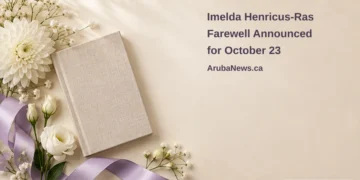 Imelda Henricus-Ras Farewell Announced for October 23 Conceptual memorial illustration of a blank closed linen-bound book, white flowers and lavender ribbon on ivory, with the article headline and ArubaNews.ca branding; no portrait or documentary scene.