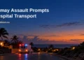 Conceptual editorial illustration, not the actual incident: an unmarked ambulance on a generic Caribbean road at dusk, with the Kamay assault headline and ArubaNews.ca branding.