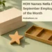 Conceptual editorial still life of a wooden star, unmarked supply box and empty sorting tray, with the article headline and ArubaNews.ca branding; not the employee or actual award.