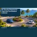 Conceptual editorial illustration: Two generic compact cars parked safely apart near a small tropical roundabout in daylight, blue and amber palette, high angle. No collision reconstruction, damage, people, plates, signs or logos. Not a photograph of the actual event, people or location.