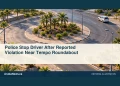 Police Stop Driver After Reported Violation Near Tempo Roundabout Conceptual editorial illustration of generic unmarked car beside an empty tropical roundabout with distant unmarked patrol vehicle, aerial angle, no real landmarks, people, plates, official insignia or writing. Not a photograph of the actual incident or location.